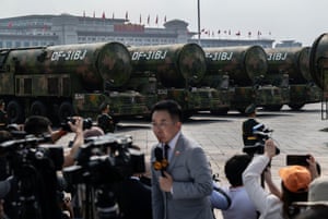 A row of nuclear missiles as part of a parade, with camera crew and a TV presenter in the foregound