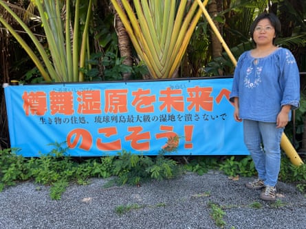 Takako Ueno, who runs a shop on Yonaguni, next to a banner she made calling for the preservation of coastal wetlands.