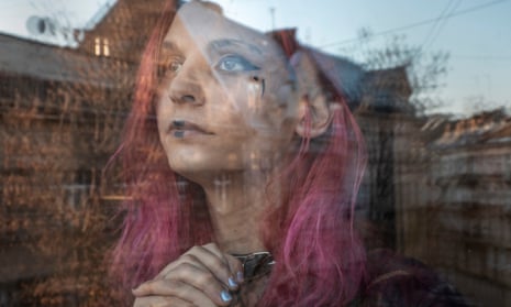 Judis, a transgender woman trapped in Ukraine, looks out through reflections in a window.