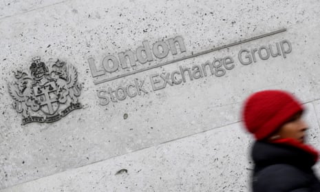 A woman walks past the London Stock Exchange building in the City of London