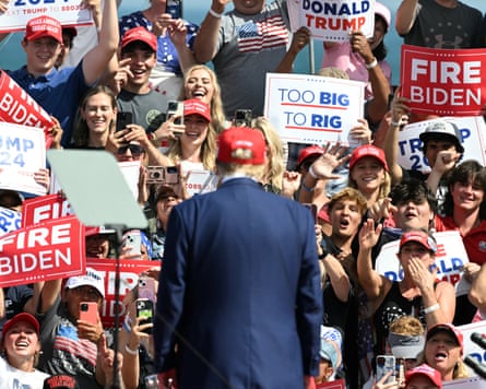 Trump at a rally with supporters holding up banners