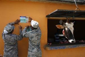 Soldiers paste up information on Zika for the public to read, next to a butcher’s shop in Guerra, Dominican Republic