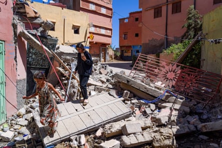 People walk among rubbles and debris from damaged buildings in the aftermath of the earthquake.