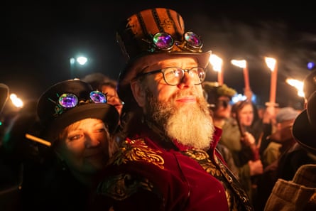 Spectators watch amid the glow of the fire pit.