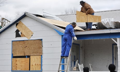 People work to board up a roof and windows of a damaged home following an outbreak of tornados in Selma, Alabama.