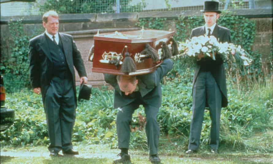 Gary Lewis bending down with a coffin on his back, in the film Orphans (1998), directed by Peter Mullan.