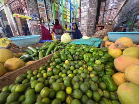 A Somali woman sitting behind a stall of limes, green peppers and melons