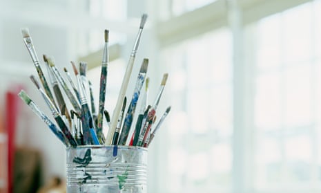 Paintbrushes in tin can on desk in classroom