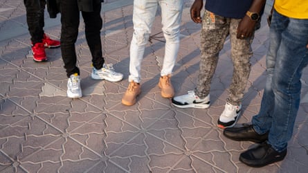 Close up image of the shoes and trousers of five men on the Corniche in Doha, Qatar.