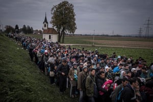 Migrants walk past the temple as they are escorted by Slovenian riot police to the registration camp outside Dobova, Slovenia, Thursday October, 22, 2015.