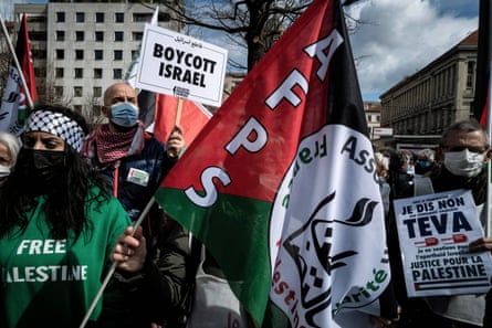 People wave the Palestine flag and hold signs that say ‘boycott Israel’