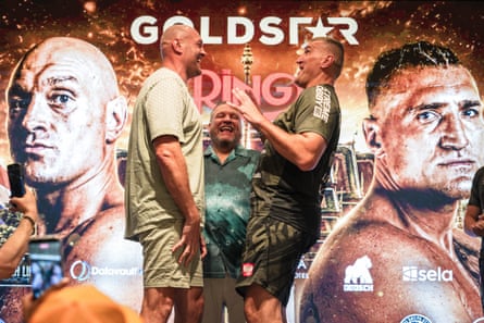 Tyson Fury (left) and Mariusz Wach laugh as they face each other in front of a promotional poster with their images on it