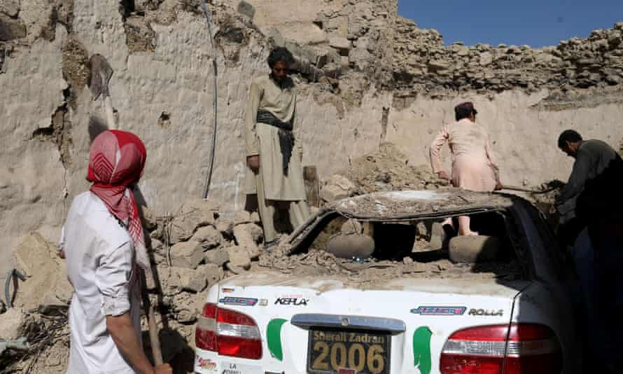 Afghan people try to retrieve a car from the debris of damaged houses after the recent earthquake