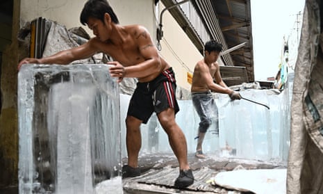 Workers move blocks of ice into a storage unit at a market during heatwave conditions, in Bangkok.