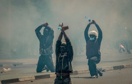 Kneeling demonstrators engulfed by teargas