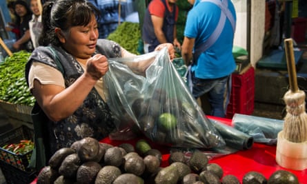 A woman prepares a bag of avocados in Mexico City
