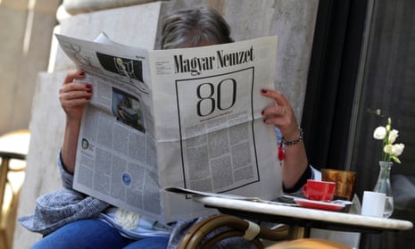 A woman reads the final edition of the Magyar Nemzet newspaper