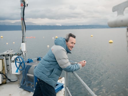 A man leans on a railing on a floating platform on Lake Geneva.