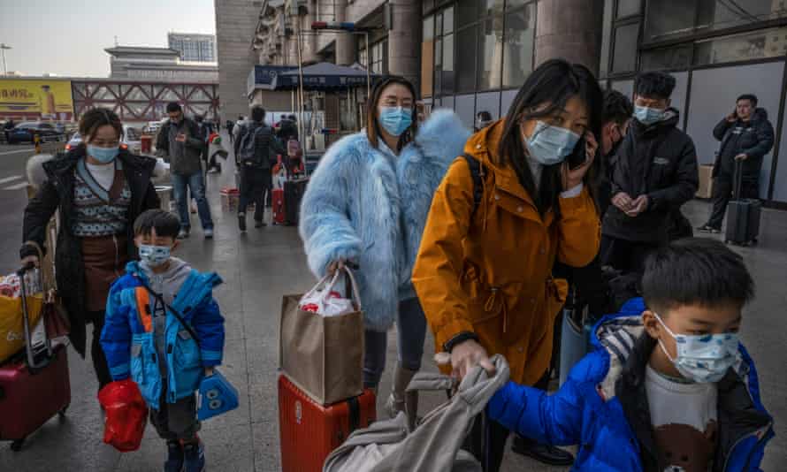 People wear protective masks in Beijing as they arrive to board trains to depart for Lunar New Year celebrations.