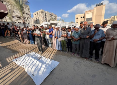 Mourners pray next to the body of a Palestinian killed by Israeli fire while seeking aid on Sunday, according to medics, at Nasser Hospital in Khan Younis, southern Gaza Strip, on 18 August, 2025.