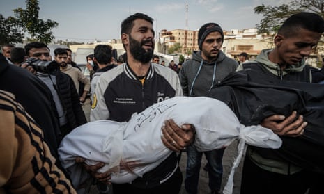 A man carries the body of a child to the morgue of Nasser hospital in Khan Younis, southern Gaza.