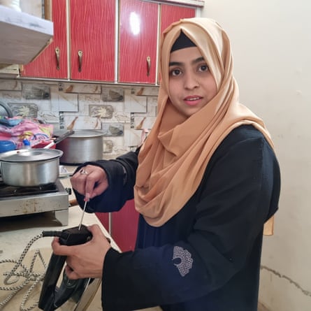 A woman in a hijab repairs an iron at a kitchen counter