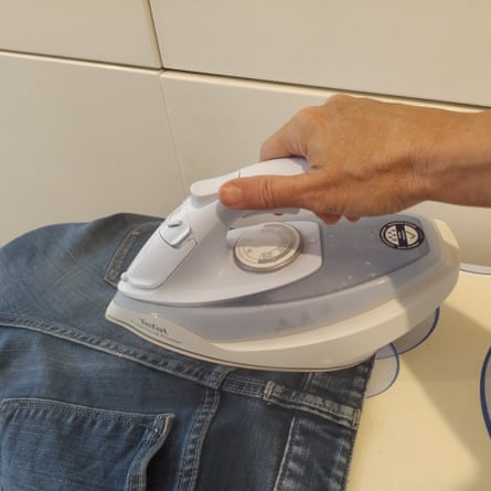 The Tefal Freemove Power is being tested on a pair of blue jeans. There is a white tiled wall in the background