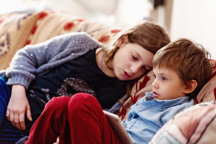 Two young children on a sofa, the younger one holding a digital tablet