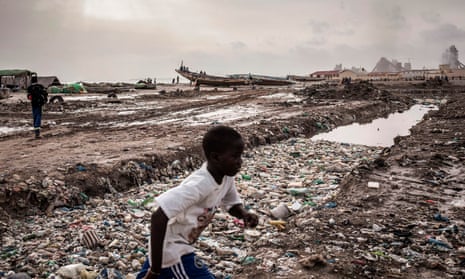 A boy runs past a large pool of putrified water along the coastline in Bargny, Senegal