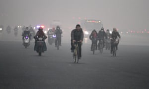 People cycle in heavy smog in Beijing.