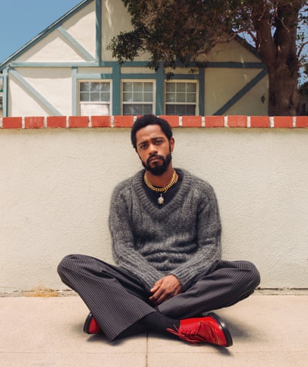 Lakeith Stanfield sits cross-legged on a terrace outside
