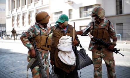 Soldiers escort a homeless woman to a gathering point in Johannesburg