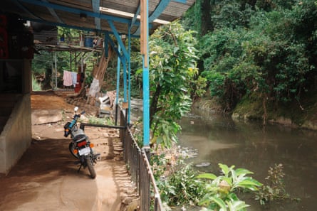 A moped parked outside a wooden house next to a river