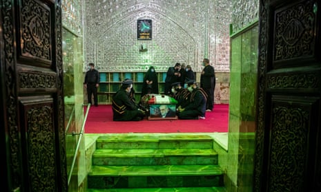 Mourners sit next to the coffin of the Iranian nuclear scientist Mohsen Fakhrizadeh in Tehran