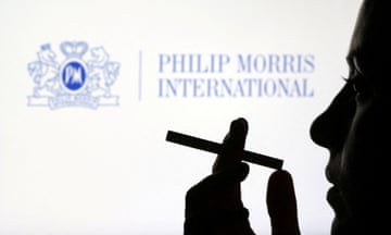 A woman seen in silhouette with a cigarette in front of the Philip Morris International logo