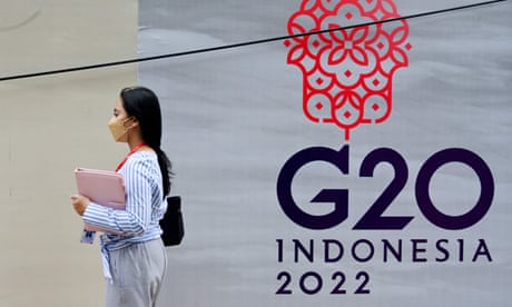 A woman walks past a logo of the G20 Summit in Jakarta, Indonesia.