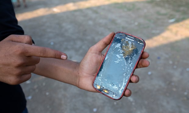 A refugees shows the cracked screen of his mobile phone