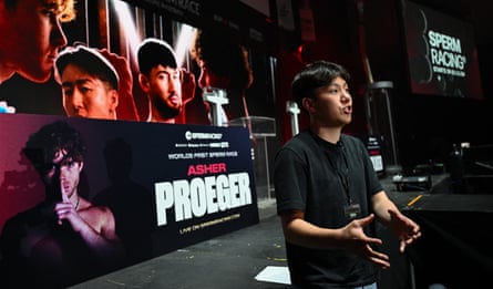A young man in a t-shirt on a stage decorated with macho posters