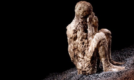 A resin cast of a crouching man covering his mouth with a hooded cloak he was wearing before he was overcome by the eruption.