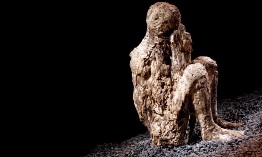 A resin cast of a crouching man covering his mouth with a hooded cloak he was wearing before he was overcome by the eruption of Mount Vesuvius.