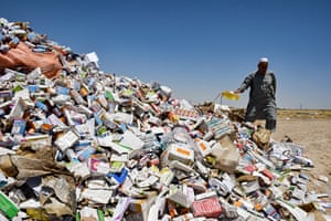 A man pours a substance over a pile of boxes of medicine