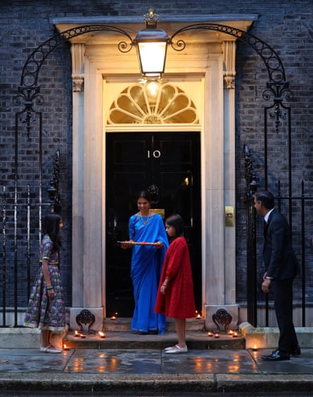 Rishi Sunak, his wife, wearing a sari, and their daughters place candles on the steps of Downing Street during Diwali