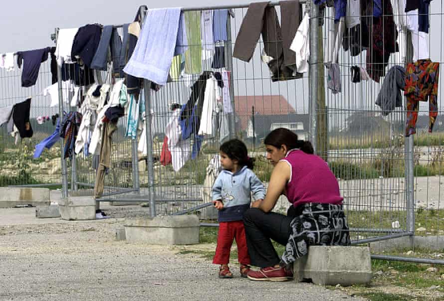 Des demandeurs d'asile attendent pendant que leurs vêtements sèchent sur une clôture du camp de réfugiés de Sangatte, dans le nord de la France.