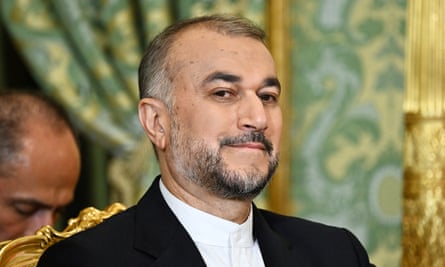Hossein Amirabdollahian sat in front of a green backdrop