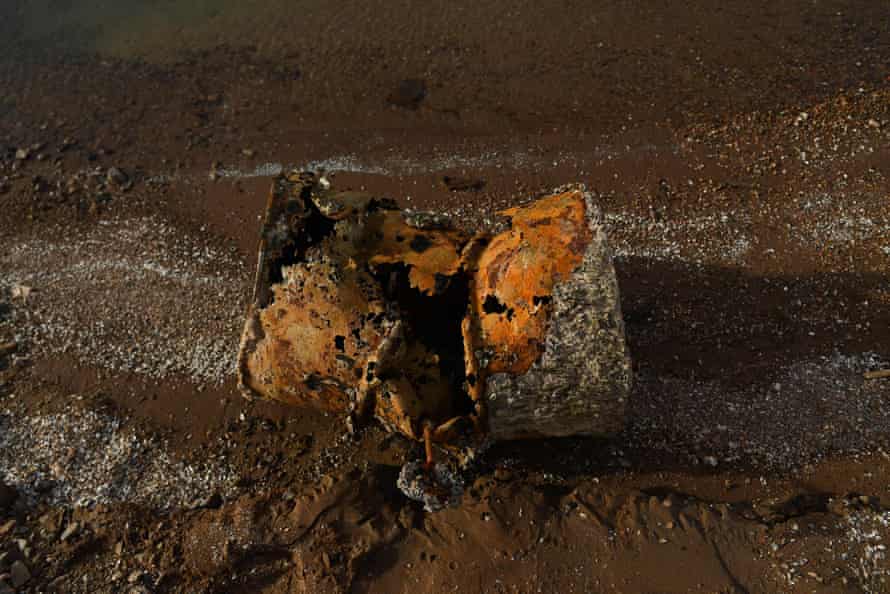 A rusted metal barrel is seen on the bottom of a dry lake bed.
