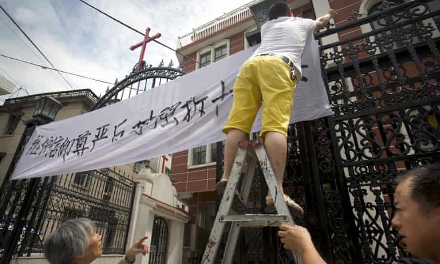 Church members put up a banner reading ‘Safeguard the dignity of belief, oppose the forcible removal of crosses’ at Jingda Catholic church, Zhejiang, in July. 