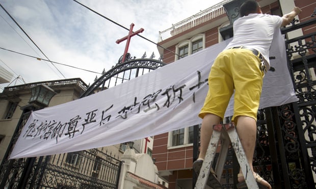 Church members put up a banner opposing the removal of crosses at a Catholic church in China’s Zhejiang province. 