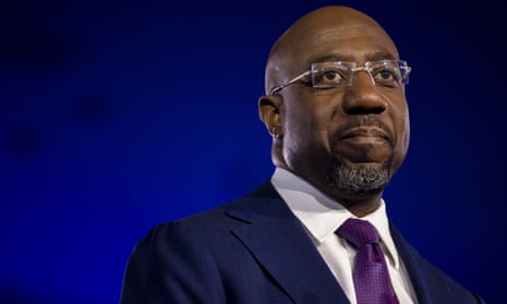 Black man with glasses wears blue suit and purple tie