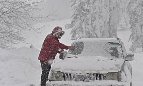 A driver clears snow from his vehicle in Casaglia, Mugello on Tuesday.