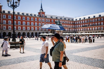 People carrying parasols in Madrid’s Plaza Mayor.